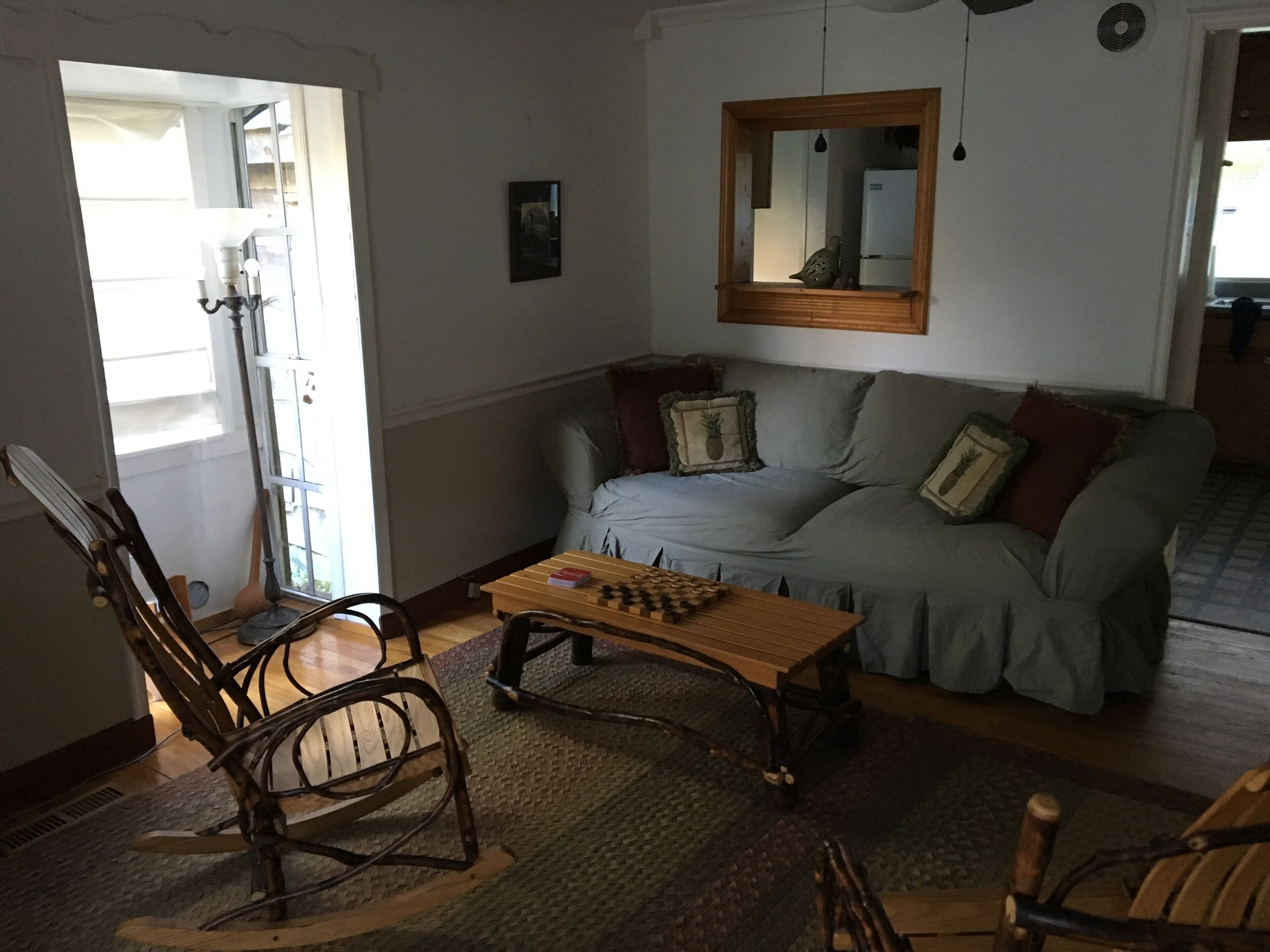 Een gezellige woonkamer met een houten salontafel, een schommelstoel en een bank met kussens.