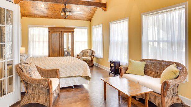 Een ruime slaapkamer met een groot bed, een houten plafond en een rieten bank.