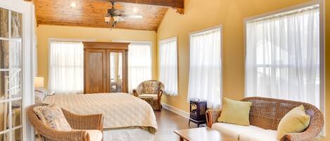 A spacious bedroom with a large bed, a wooden ceiling, and a wicker sofa.