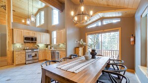 Une cuisine spacieuse avec des meubles en bois, une grande table à manger et un lustre.