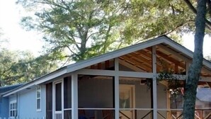 Een gelijkvloers huis met een overdekte veranda en een witte picket fence.