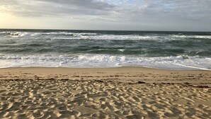 Ein Strand mit Wellen und einem bewölkten Himmel.