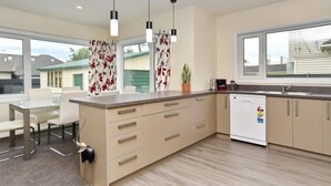 A modern kitchen with a central island, pendant lights, and a view of neighboring houses. - Room to spread out · fenced lawn, pets welcome - Weston Villa (St Albans)