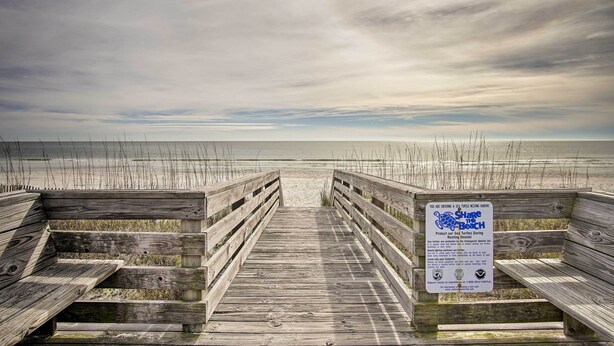 A wooden boardwalk leading to a beach with a sign about sea turtle habitat. - Gulf Shores Getaway w/ Pool, Spa & Beach Access! (Gulf Shores)