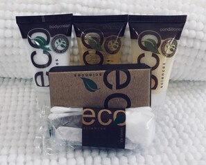 Une gamme de produits de soins personnels écologiques, comprenant une crème pour le corps, un shampooing, un après-shampooing et une trousse de toilette.