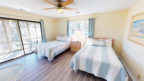 A bedroom with two beds, a ceiling fan, and a view of the outdoors through large windows. - Golf Course Comfort Awaits with views (CV4A) (Sunset Beach)