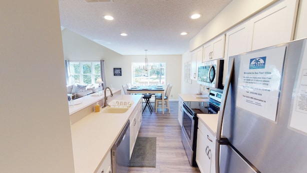 A modern kitchen with a dining area, large windows, and a view of the outdoors. - Golf Course Comfort Awaits with views (CV4A) (Sunset Beach)