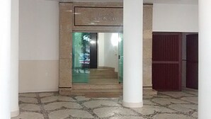 Un couloir avec un sol à motifs, un pilier blanc et une porte sur laquelle est apposée une enseigne.