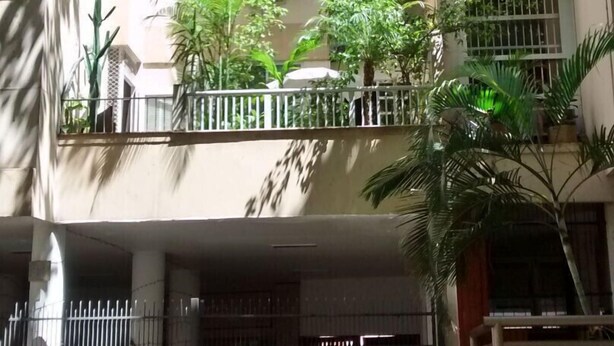 Un immeuble à plusieurs étages doté de balcons, de climatiseurs et d’une entrée sécurisée par un portail.