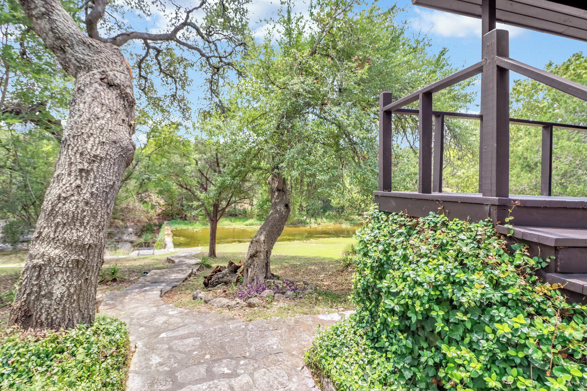 A pathway leading to a wooden structure with a view of a pond and trees.