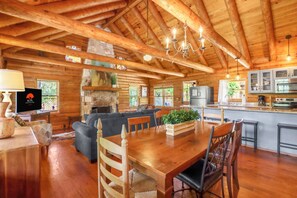A spacious lodge interior with a dining area, kitchen, and living room. - Hill Country Log Cabin Near Wimberley | Hot Tub, Fire Pit & Scenic Views (Wimberley)