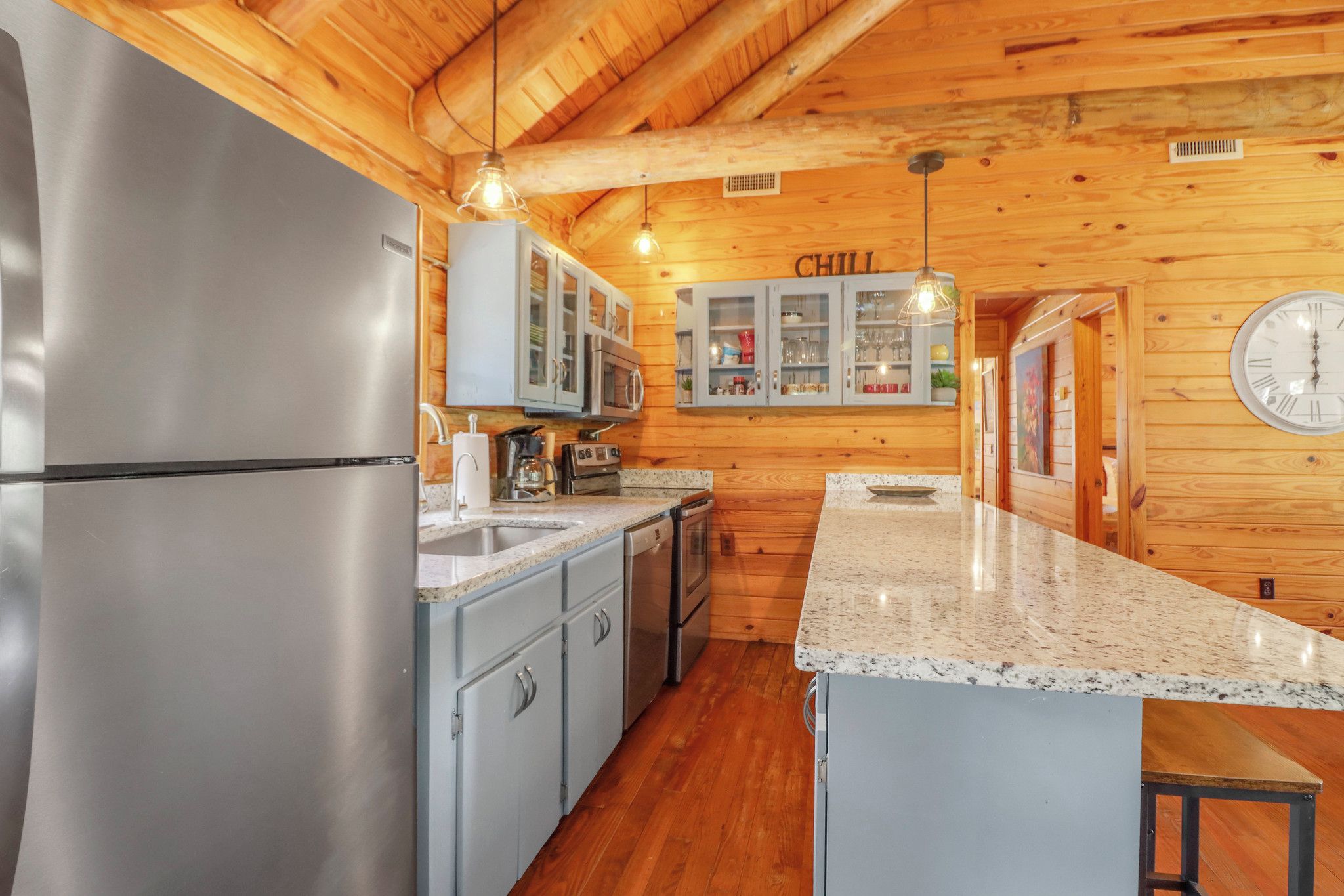 A kitchen with wooden walls, stainless steel appliances, and a granite countertop.