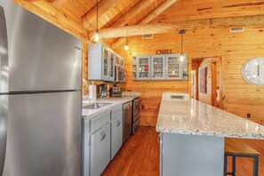 A kitchen with wooden walls, stainless steel appliances, and a granite countertop.