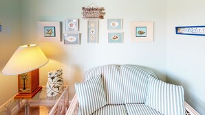 Una habitación con una silla a rayas, una lámpara y cuadros en la pared.