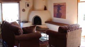 A cozy living room with a fireplace, two armchairs, and a sofa.