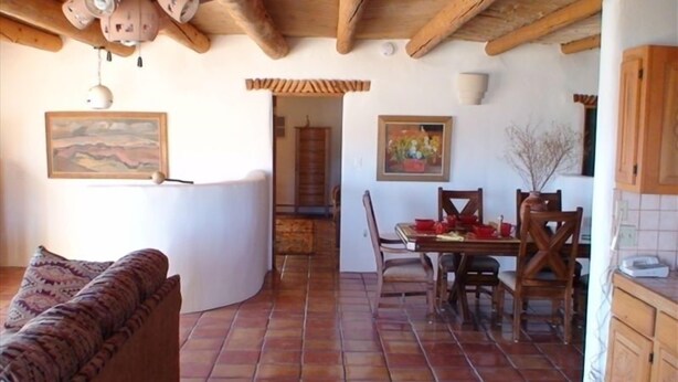 A cozy living area with a sofa, a dining table with chairs, and a kitchen area with wooden cabinets.