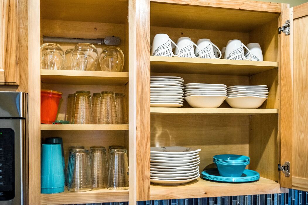Un meuble en bois doté d’étagères où sont rangés des bocaux en verre, des assiettes et des tasses.