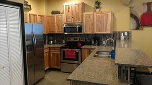 A kitchen with wooden cabinets, stainless steel appliances, granite countertops, and a tiled backsplash. - Secluded Nampa Idaho Home, Near Shopping (Nampa)