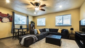 A living room with a sectional sofa, a coffee table, a ceiling fan, and a dining area with a table and chairs. - Secluded Nampa Idaho Home, Near Shopping (Nampa)