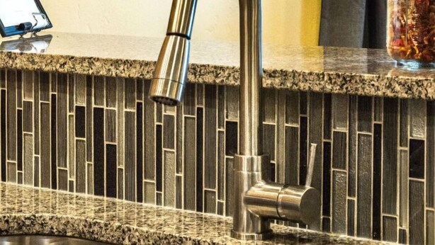 A kitchen with a granite countertop, stainless steel sink, and a backsplash with a mosaic tile pattern. - Secluded Nampa Idaho Home, Near Shopping (Nampa)