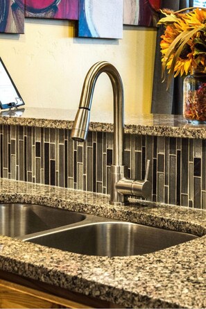 A kitchen with a granite countertop, stainless steel sink, and a backsplash with a mosaic tile pattern. - Secluded Nampa Idaho Home, Near Shopping (Nampa)