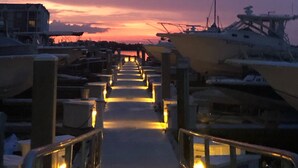 A marina with boats docked and a walkway leading towards a sunset. - Harbour Village: golf, two beds, two baths, marina, and most spectacular beach.  (Ponce Inlet)
