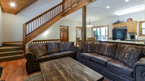 A spacious living room with a wooden staircase, a large sofa set, and a kitchen area in the background. - Indoor Pool - Sleeps 22 - 8 King Beds - Right by SDC - Vanessa's Vacation Homes (Branson)
