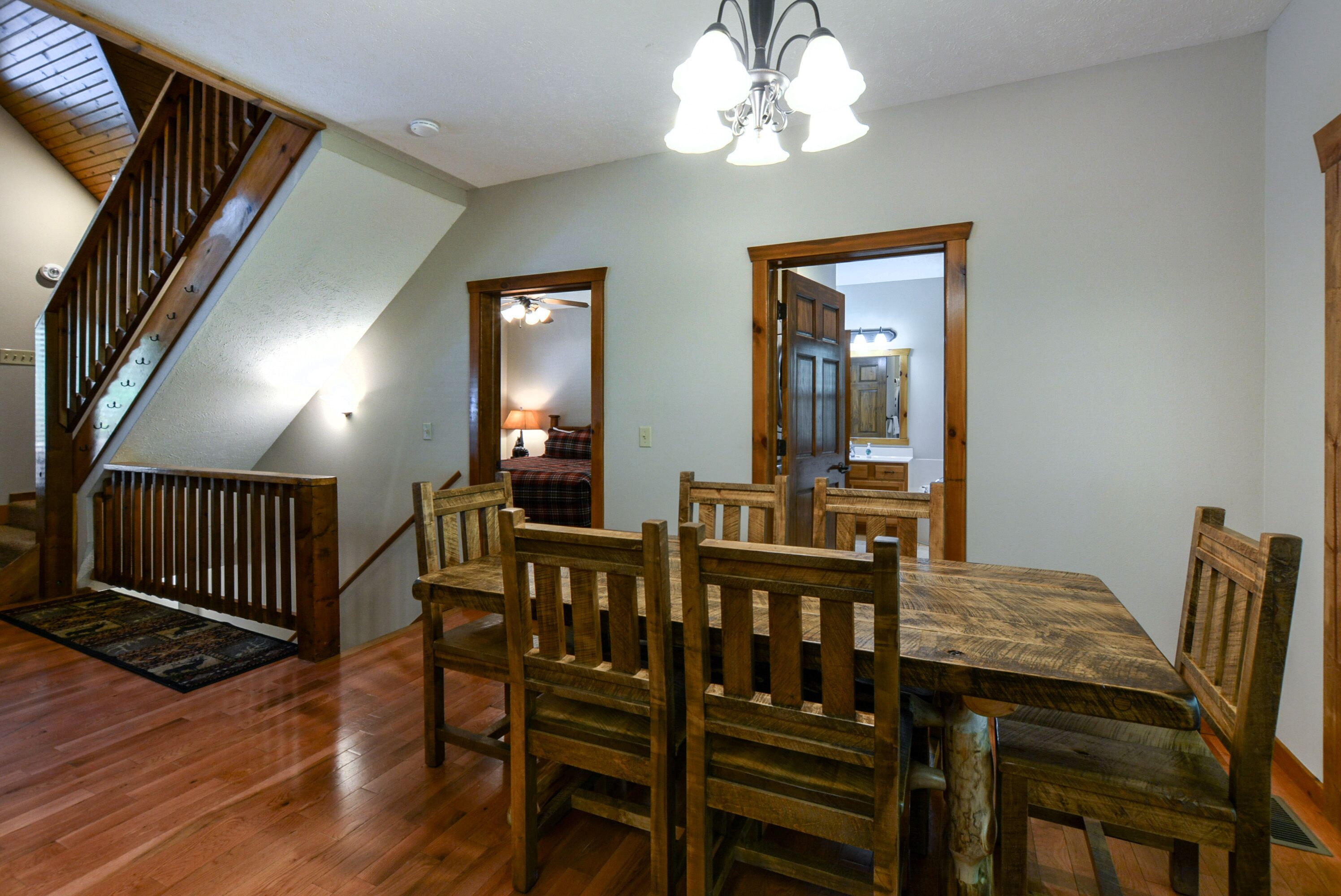A dining area with a wooden table and chairs, a staircase, and a ceiling light fixture.
