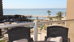 A balcony with wicker chairs and a table overlooking a beach and pool area. - 2 Kings plus Bunk Bed Room 3rd floor Huge Patio (Puerto Penasco)