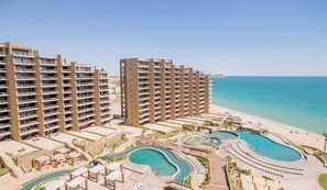 A resort with multiple high-rise buildings, a large pool area, and a beach.
