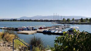 Ein Yachthafen mit vertäuten Booten, eine Anlegestelle und Berge im Hintergrund.