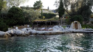 A serene outdoor pool area with a stone pathway, lounge chairs, and a rustic archway. - Beach Front, Romantic Escape, Breathtaking Views, 'Pieds dans L'eau', & More (Magnesia)