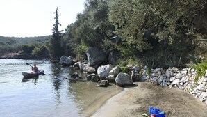 A riverbank with a kayak, rocks, and a stone wall. - Beach Front, Romantic Escape, Breathtaking Views, 'Pieds dans L'eau', & More (Magnesia)