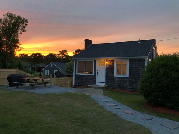 A house with a front porch, a barbecue grill, and a picnic table.