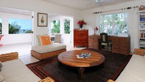 Un salón espacioso con una mesa redonda de madera, un sofá con cojines, un armario rojo y una estantería.