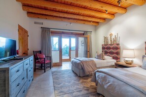 Un dormitorio con dos camas, televisión, cómoda y un ventanal grande.
