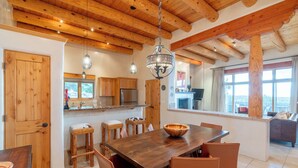 A spacious kitchen with wooden cabinets, a large wooden dining table, and a hanging light fixture. - Bishop's Lodge Villa 43D | Views & Luxury (Santa Fe)