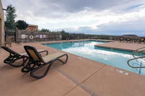 Una piscina con sillas de descanso, un letrero de socorrista y vistas a las colinas.
