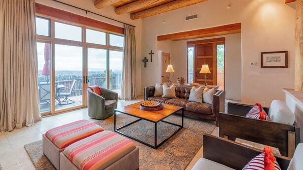 A spacious living area with a large window, a sofa, a coffee table, and a view of the city. - Bishop's Lodge Villa 43D | Views & Luxury (Santa Fe)