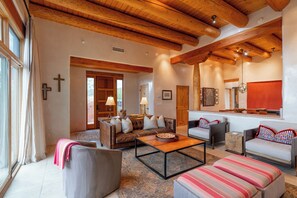 Amplia sala de estar con techo de madera alto, chimenea y ventana grande.