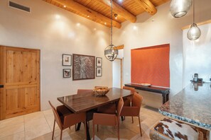 Un comedor con una mesa de madera, sillas y una lámpara colgante.