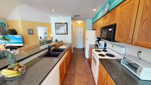 A modern kitchen with granite countertops, wooden cabinets, a built-in oven, and a microwave.