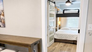 A compact room with a bunk bed, a desk with two chairs, and a small table.