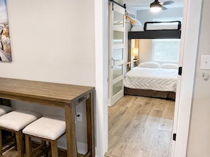 A compact room with a bunk bed, a desk with two chairs, and a small table.