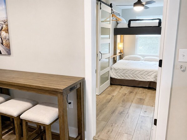 Ein kleines Zimmer mit einem Etagenbett, einem Schreibtisch und zwei Stühlen sowie einem kleinen Tisch.