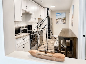 A kitchen with white cabinets, a built-in microwave, and a wooden cutting board. - #101 Ocean Inn 2 Bedroom 1.5 Bath Modern Favorite (Isle of Palms)