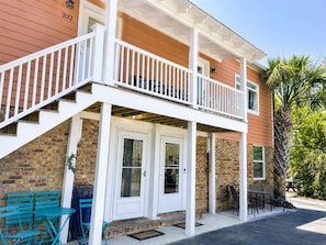 A two-story building with a balcony, a brick facade, and a door marked with the number 102.