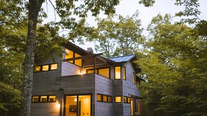 Ein modernes, zweistöckiges Haus mit großen Fenstern und einem sichtbaren Innenraum.