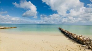 A beach with clear turquoise water, a sandy shore, and a wooden jetty extending into the sea. - La Tintinki, amaizing ocean view!! (Chelém)