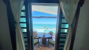An open door leading to a terrace with a table and chairs, overlooking a beach. - La Tintinki, amaizing ocean view!! (Chelém)